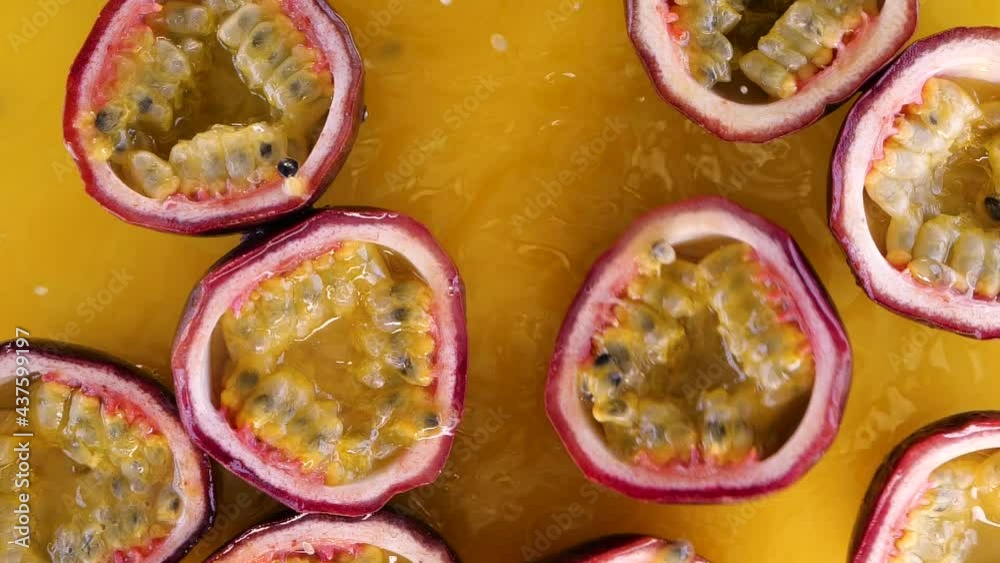 Passion fruit falling and splashing into water on yellow background in slow motion.  Juicy fresh summer passion fruits splashing into juice.