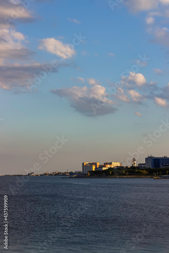 Coastline of a modern coastal town at sunset. Church and high-rise residential buildings on the seashore. Vertical orientation. Portrait orientation.