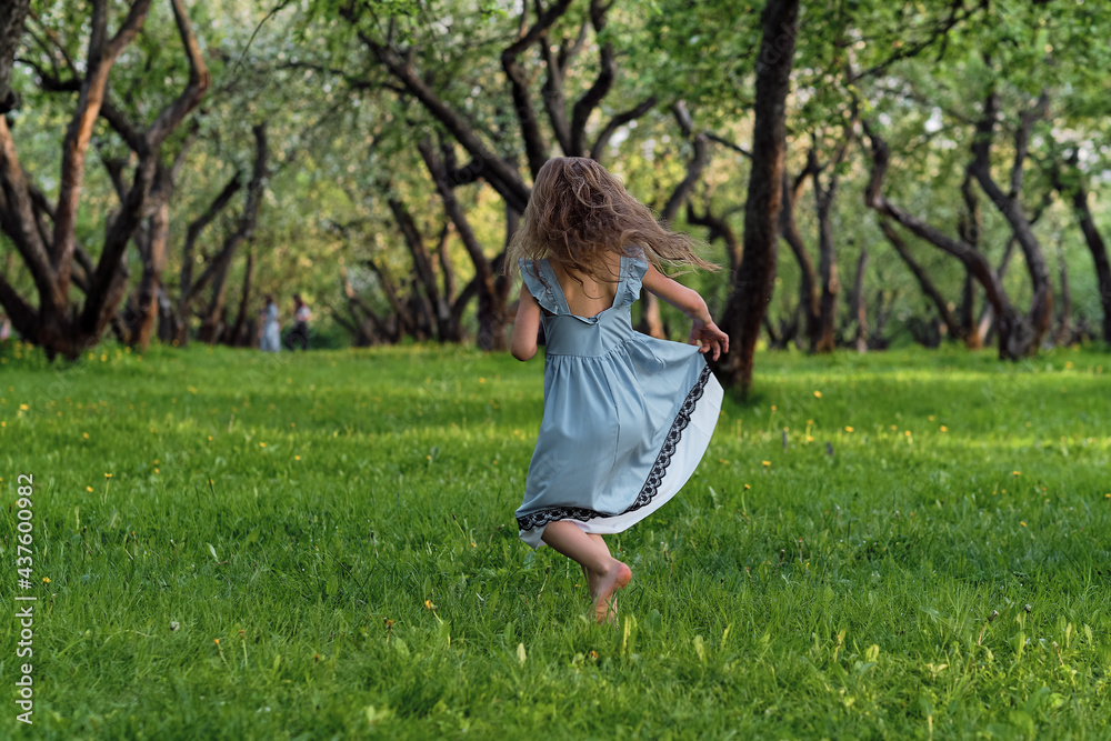 little girl runs barefoot on the grass. happy child on a hot summer day. little girl runs barefoot on the grass. happy child on a hot summer day.