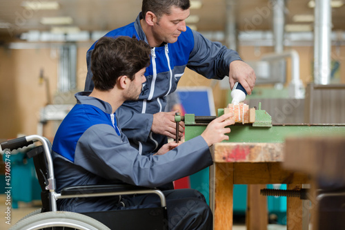 mentor and disabled worker in wheelchair in factory