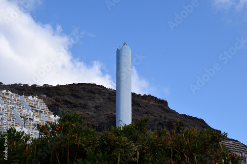Tall Concrete Chimney Isolated against Green Hillside & Blue Sky 