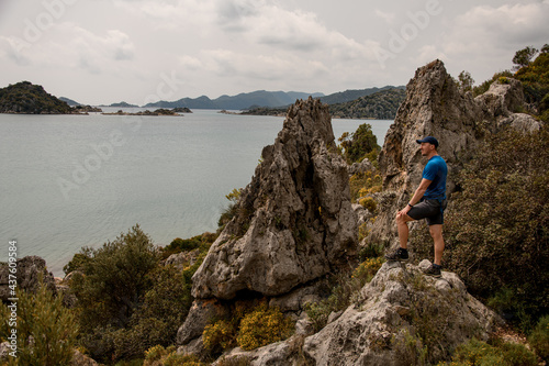 side view of man standing on large stone against the backdrop of magnificent landscape © fesenko