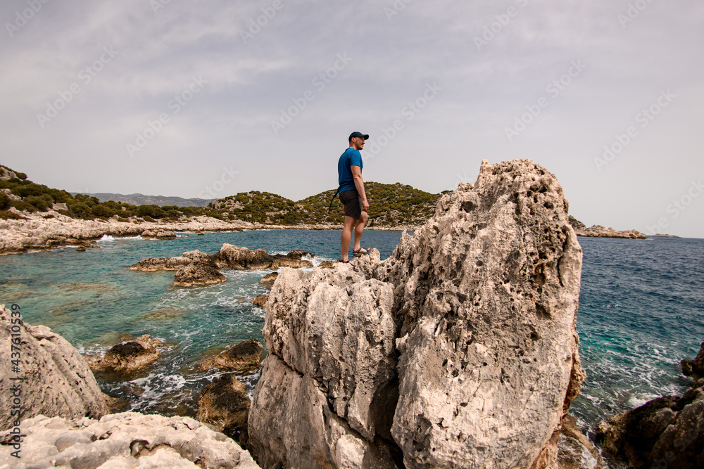 man stands on large stone on the seashore against the backdrop of landscape