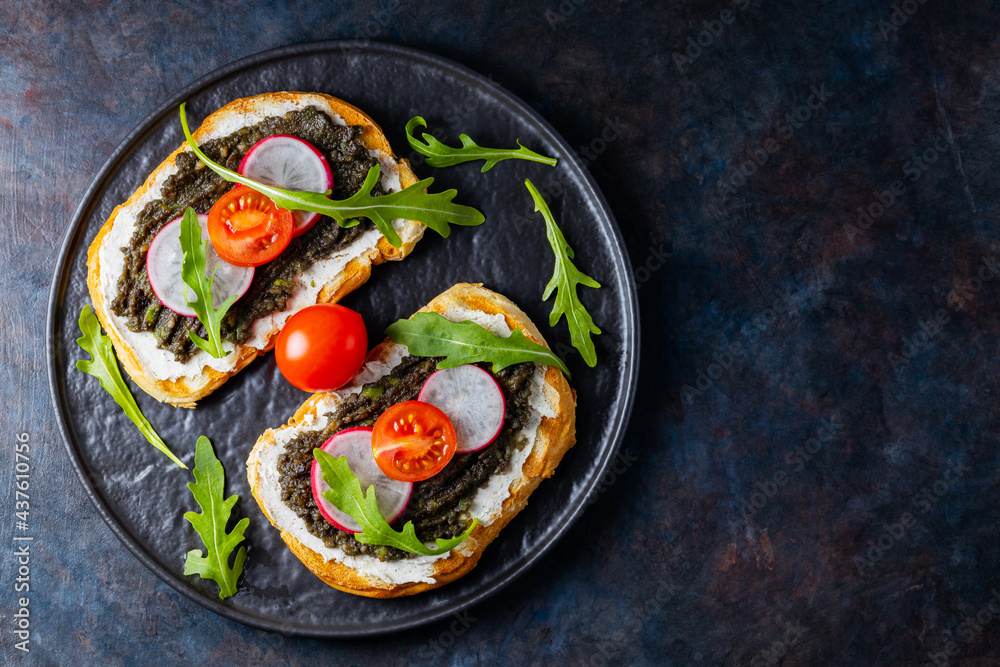 Healthy food. Avocado toasts with avocado, cream cheese and radish. Toasts with avocado, arugula and cherry tomatoes on a dark background. Copy space. Top view Healthy food. Avocado toasts with avocado, cream cheese and radish. Toasts with avocado, arugula and cherry tomatoes on a dark background. Copy space. Top view