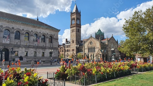 Old church in a street with flowers, trees, sky and historic buildings photo