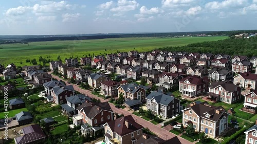 Aerial drone view shot of real estate. Summer sunny day. Suburban neighborhood residential houses. Establishing shot of suburb, streets. Residential single family houses.