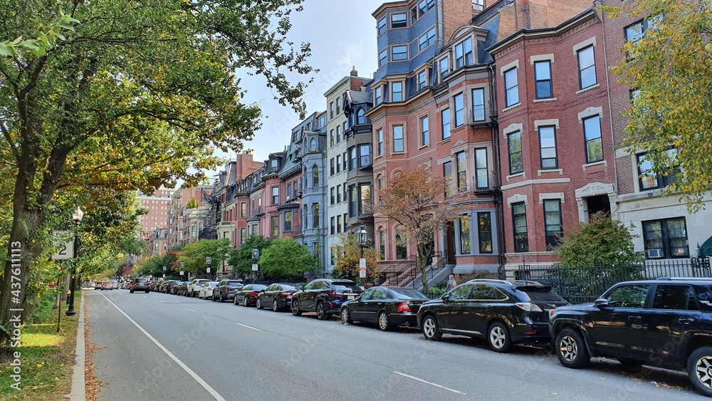 Obraz premium old town street with red buildings, park and black cars line