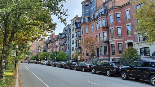 old town street with red buildings  park and black cars line