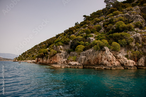 view from the water to forested hill with the ruins of the sunken city