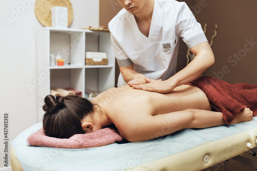 A professional massage therapist conducts a back massage for a woman client in his office, manual therapy of the spine