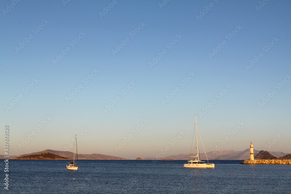 Seascape at sunshine. Lighthouse and sailings on the coast. Seaside town of Turgutreis and spectacular sunshine. 