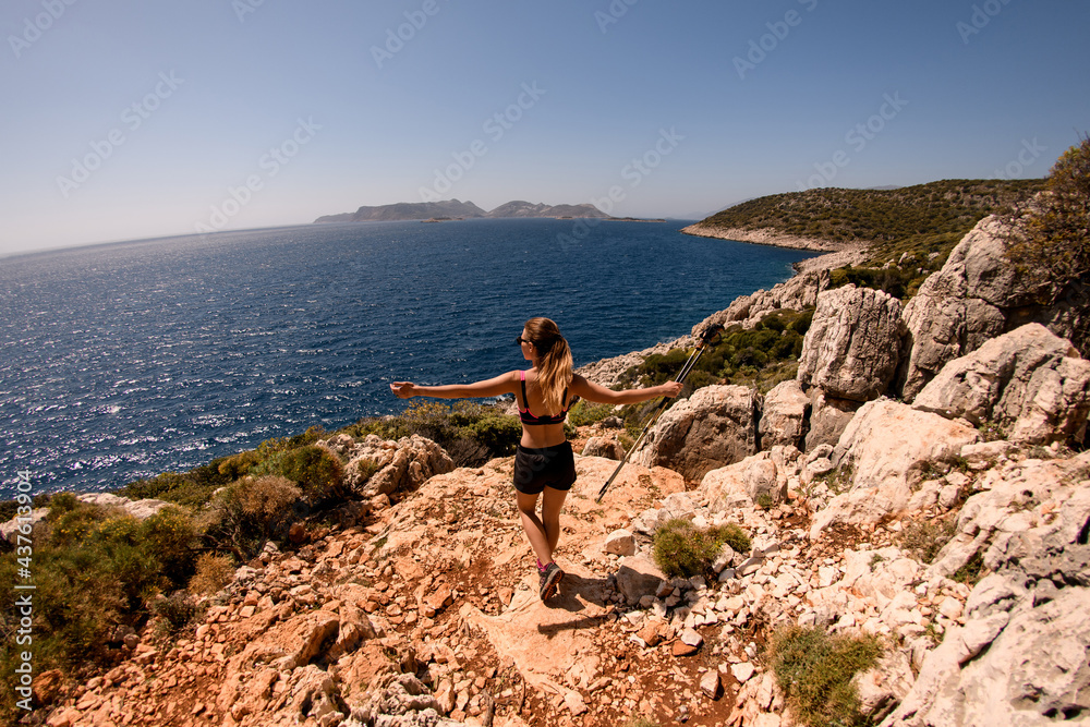 rear view of woman spreading her arms wide to the sides on seascape background.