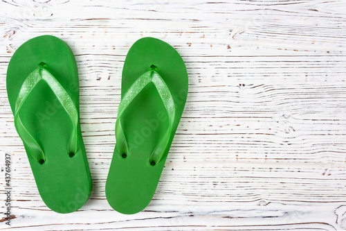 green rubber slippers on a white wooden background, view from above, place under the text