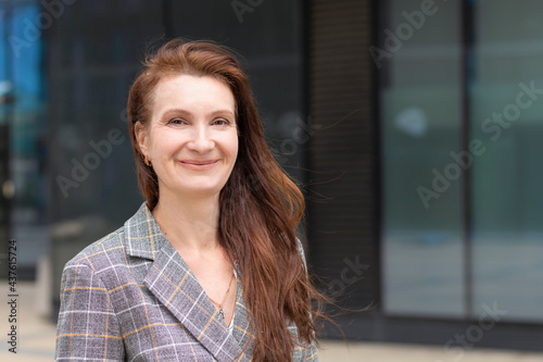 portrait of happy kind adult woman. mature middle age businesswoman smiling. lady with long brunette ginger hair with smile. positive professional, teacher outdoors, looking at the camera