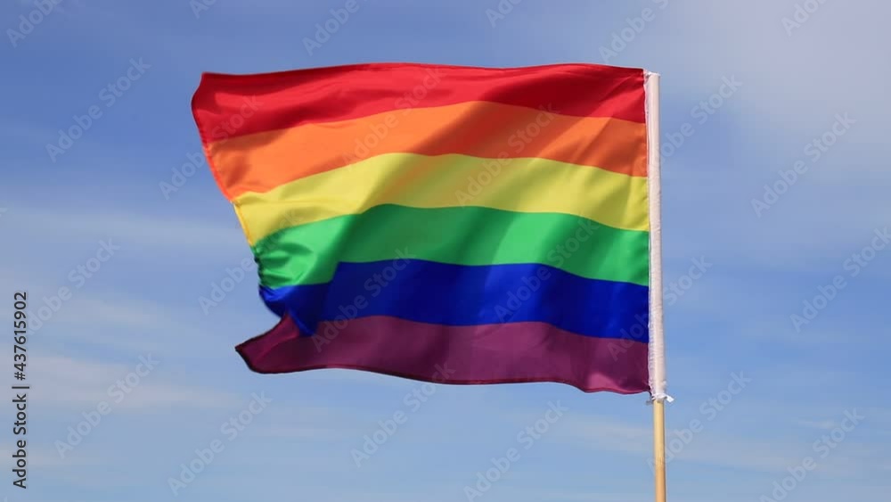 Waving gay pride rainbow flag in blue summer sky. Bright flag of the LGBT community for lesbian, gay, bisexual, transgender. Waving gay pride rainbow flag in blue summer sky. Bright flag of the LGBT community for lesbian, gay, bisexual, transgender.
