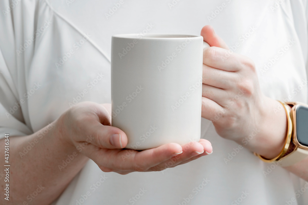 Female hands holding big beige mug with empty surface for design. Female hands holding big beige mug with empty surface for design.