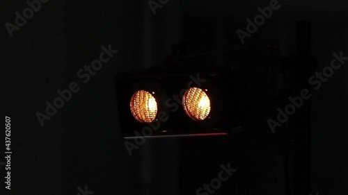 Two bright spotlights flash on stage, then flash brightly, in a loop, on the background of strobe lights