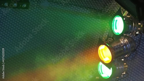 Three classic stage spotlights flash in the fog under the stage ceiling