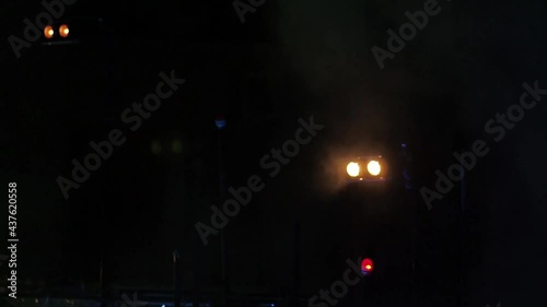 Twin spotlights and multiple red lights flash in the dark on stage