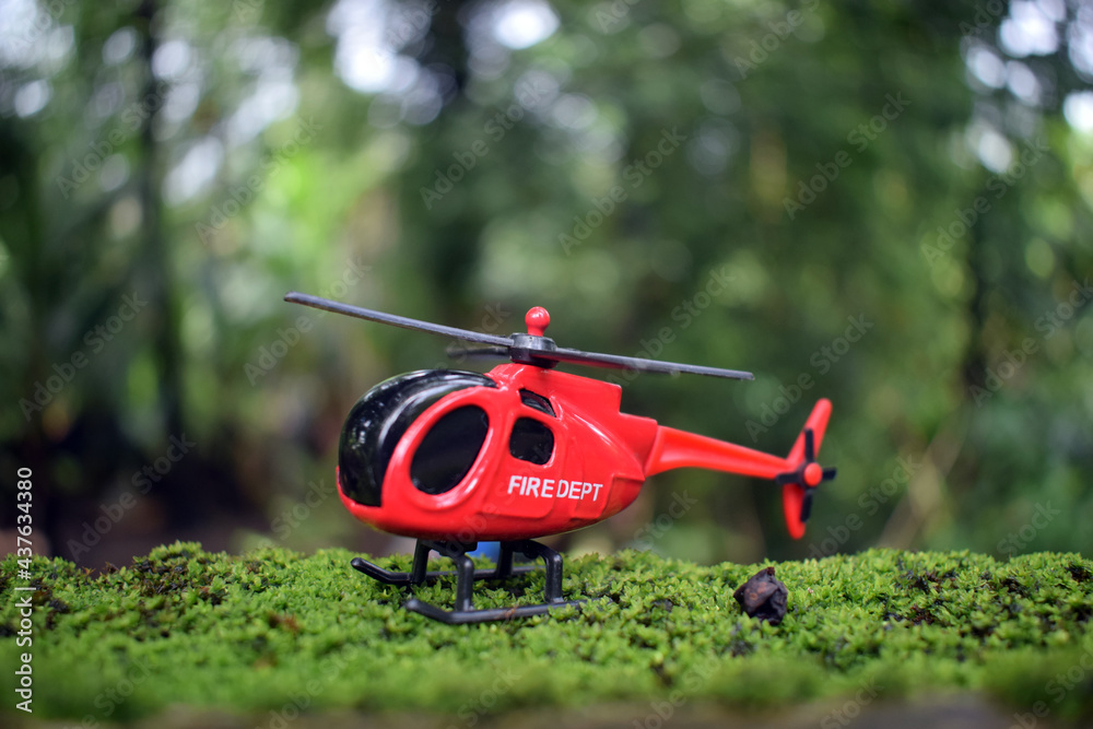 Toy fire department red colour helicopter landed on a green moss plants Toy fire department red colour helicopter landed on a green moss plants