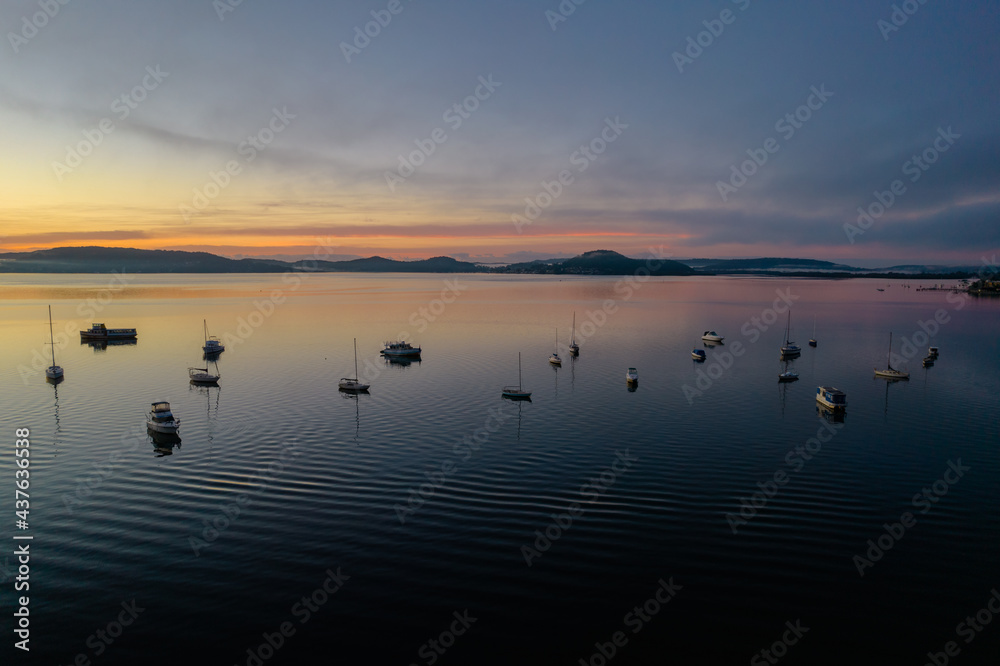 Sunrise waterscape with boats, light cloud and fog Sunrise waterscape with boats, light cloud and fog