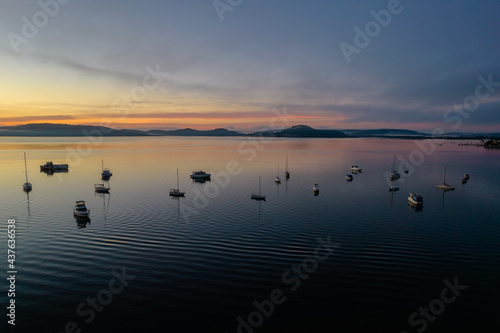 Sunrise waterscape with boats  light cloud and fog
