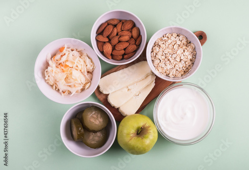 Probiotics food on light green background. Sauerkraut, pickled cucumbers, natural yogurt, cheese, almond, oatmeal and apple. Top view, flat lay