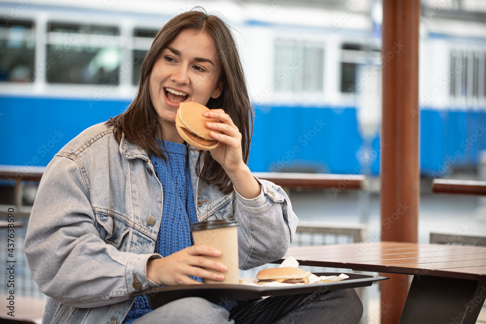 Street portrait of cheerful young woman eating fast food. Street portrait of cheerful young woman eating fast food.