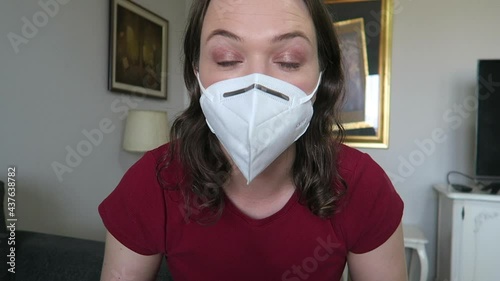 Pretty girl putting on mascara/makeup wearing a white face mask