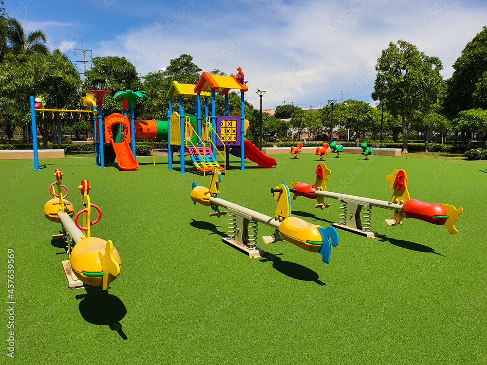 Seesaw at colorful children playground on green yard activities,public park  surrounded by green trees with sunlight morning. Children run,slide,swing  on modern playground.Urban neighborhood childhood Stock Photo | Adobe Stock