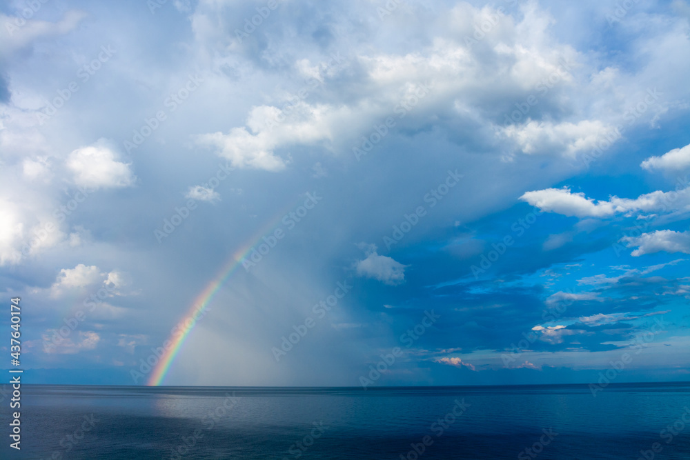 Rainbow over Lake Baikal with rain clouds in the sky. Horizontal image.