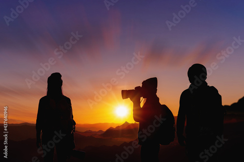 Young woman photographer taking photo her friend with sunset on mountain natural background.