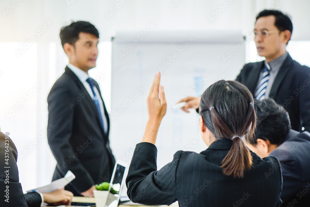 Asian business woman rising hand for asking question while meeting in office. leader coach trainer on educational lecture seminar workshop with mixed race colleagues in office. Asian business woman rising hand for asking question while meeting in office. leader coach trainer on educational lecture seminar workshop with mixed race colleagues in office.