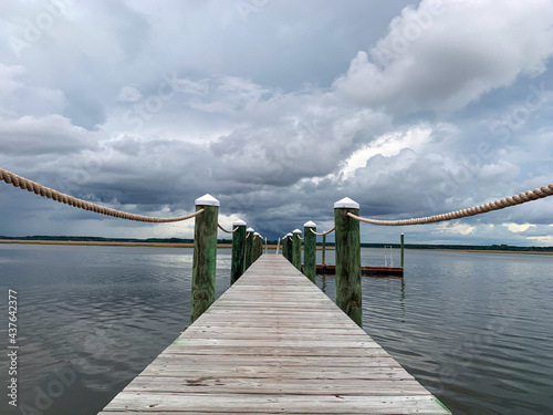 Wooden dock with ropes on stormy cloudy day over water on salt marsh