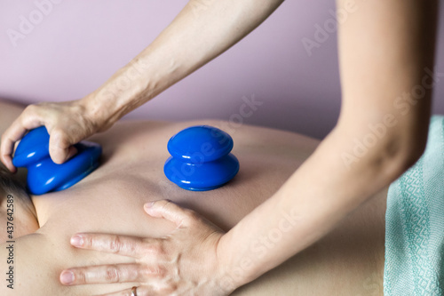 A postpartum doula gives a woman a back massage with vacuum silicone cups. Postpartum recovery of a woman. High quality photo