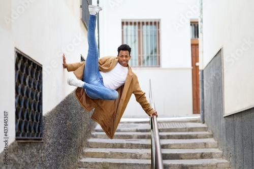 Photography Young black man jumping for joy over a handrail in the street.