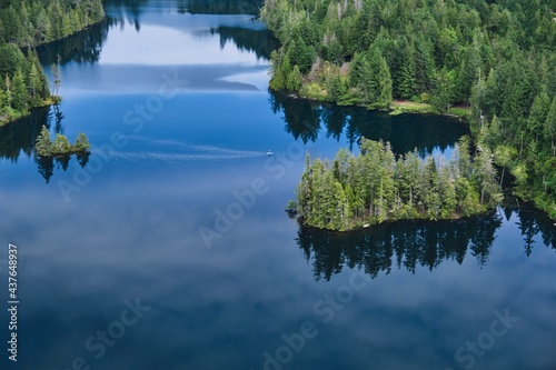 Person on paddle board on the calm lake with islands and reflections in water. View from above. Lily lake in Madeira Park. Sunshine Coast. British Columbia. Canada 
