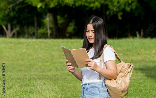 Asian teenage woman reading a book in the outdoors isolated on natural background, Asian student education