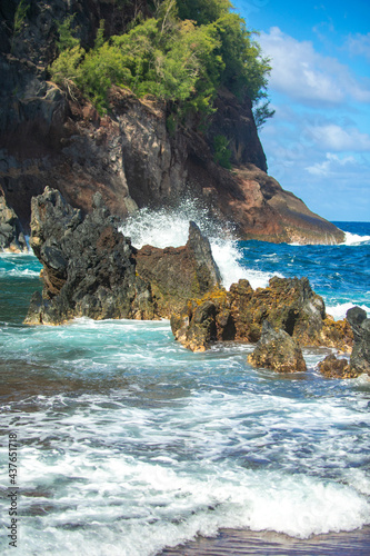 Ocean waves crashing on the rocky island coast. Splashing ocean waves and stones. Red Sand Beach, Maui in in Hawaiian.