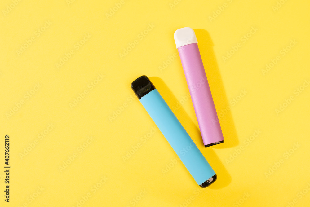 disposable electronic cigarettes with shadow on a yellow background with copy space. The concept of modern smoking, vaping and nicotine. top view.