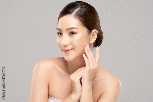 Wellness Asian young woman touch her cheek clean fresh and nutural pure skin,Pretty girl smile be moist skin on face shining like a model,Facial treatment of beauty woman,isolated on gray background