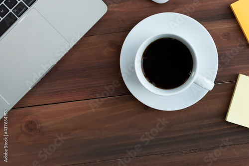 Top view of Business equipment Computer laptop notebook,post it and coffee cup on wooden table,Flat lay business concept with copy space