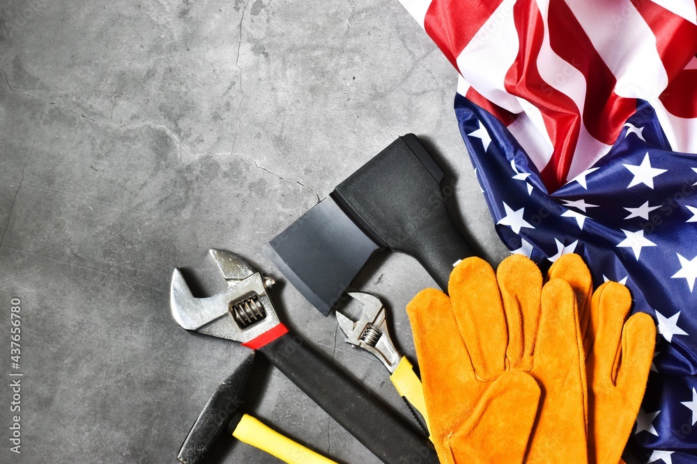 HAPPY LABOR DAY. Hammer, ax, monkey wrenches and flag of America, gloves on gray background. The concept of the holiday, labor day. Flat lay.