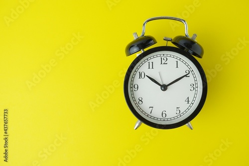 black alarm clock isolated on yellow background