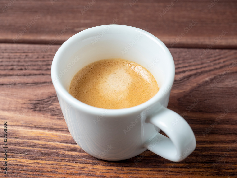 a white cup with a delicious and aromatic espresso on a wooden background. side view a white cup with a delicious and aromatic espresso on a wooden background. side view