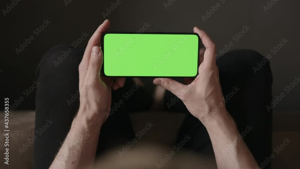 POV top view shot of man using phone with green screen indoor sitting on a couch POV top view shot of man using phone with green screen indoor sitting on a couch