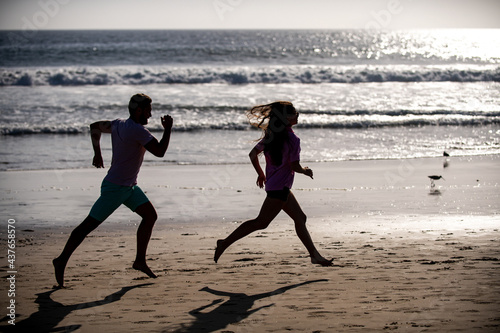 Sport and healthy lifestyle, friends jogging at sunset on the beach. Silhouette couple running on beach.
