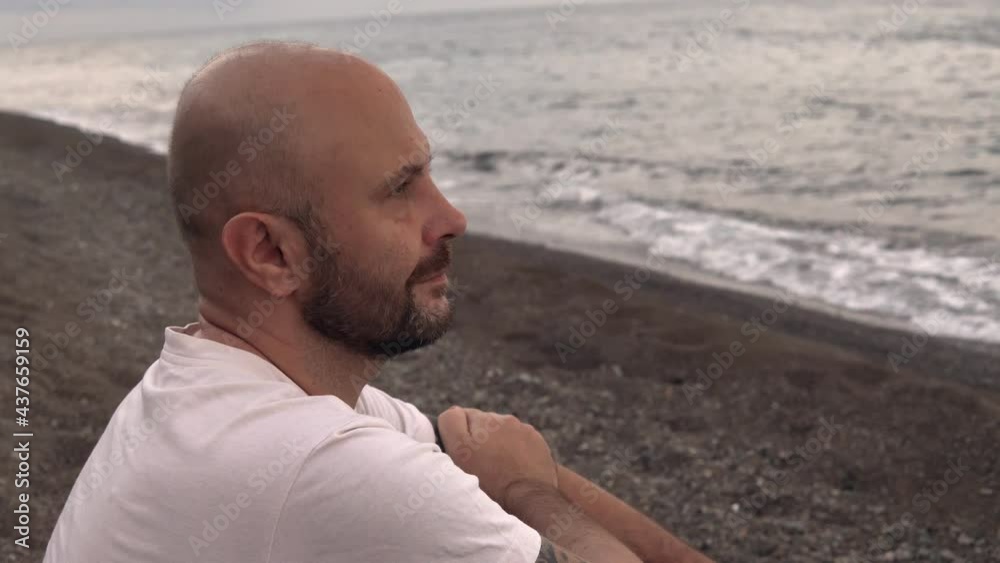 A man admires the beautiful sky sitting on the seashore. 4k footage A man admires the beautiful sky sitting on the seashore. 4k footage