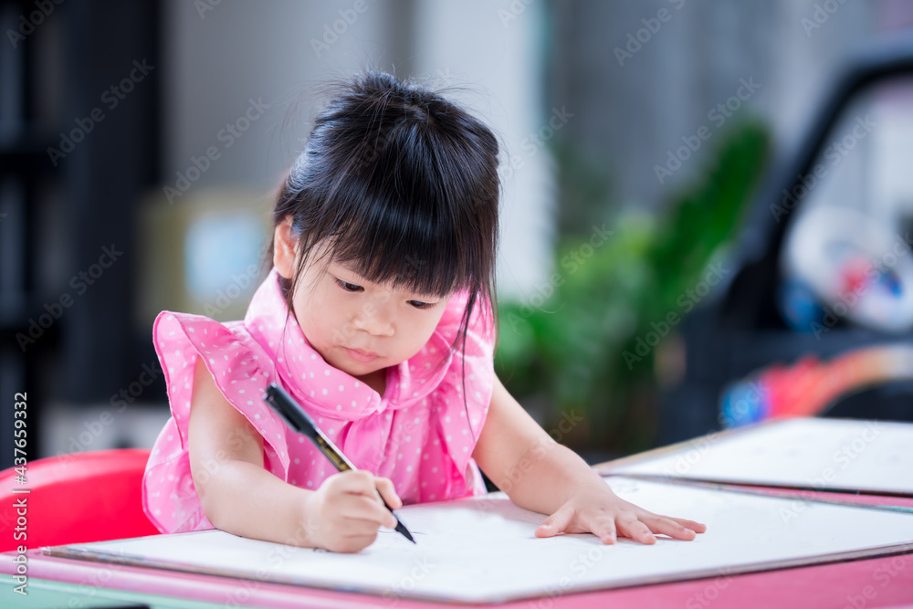 Cute child doing artwork on red desk. Asian girl drawing cartoon on paper. Happy kid learning at home. Children aged 4 years old. Cute child doing artwork on red desk. Asian girl drawing cartoon on paper. Happy kid learning at home. Children aged 4 years old.