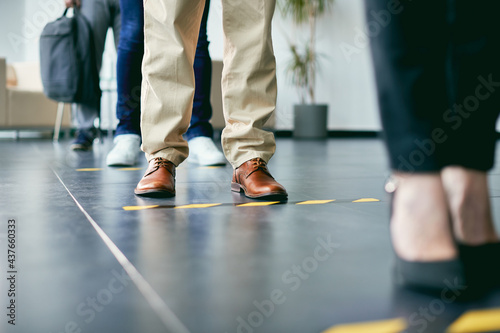 Close-up of business people standing in a row behind social distance lines at office building. photo